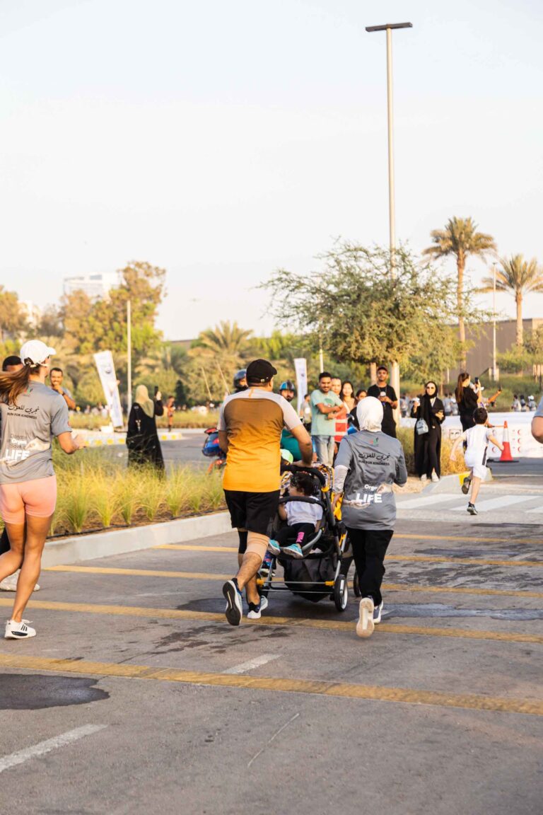 Parents running with their child in a stroller at Zayed Charity Marathon Abu Dhabi 2022