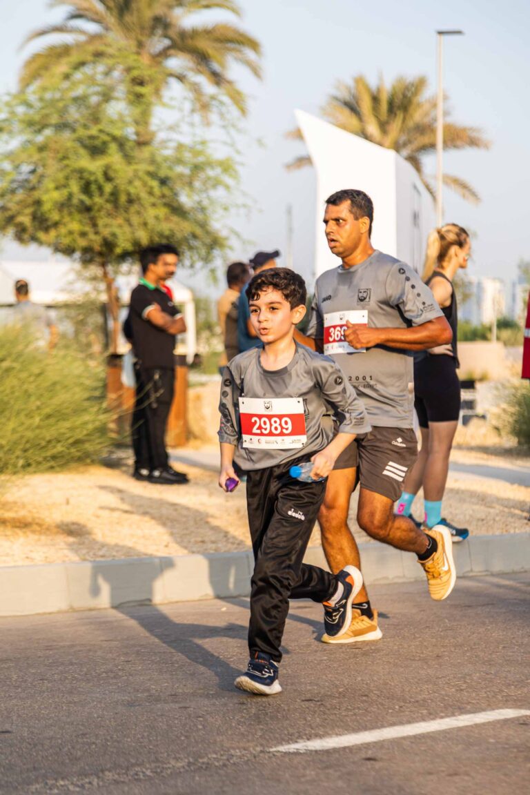 Child running with father at Zayed Charity Marathon Abu Dhabi 2022