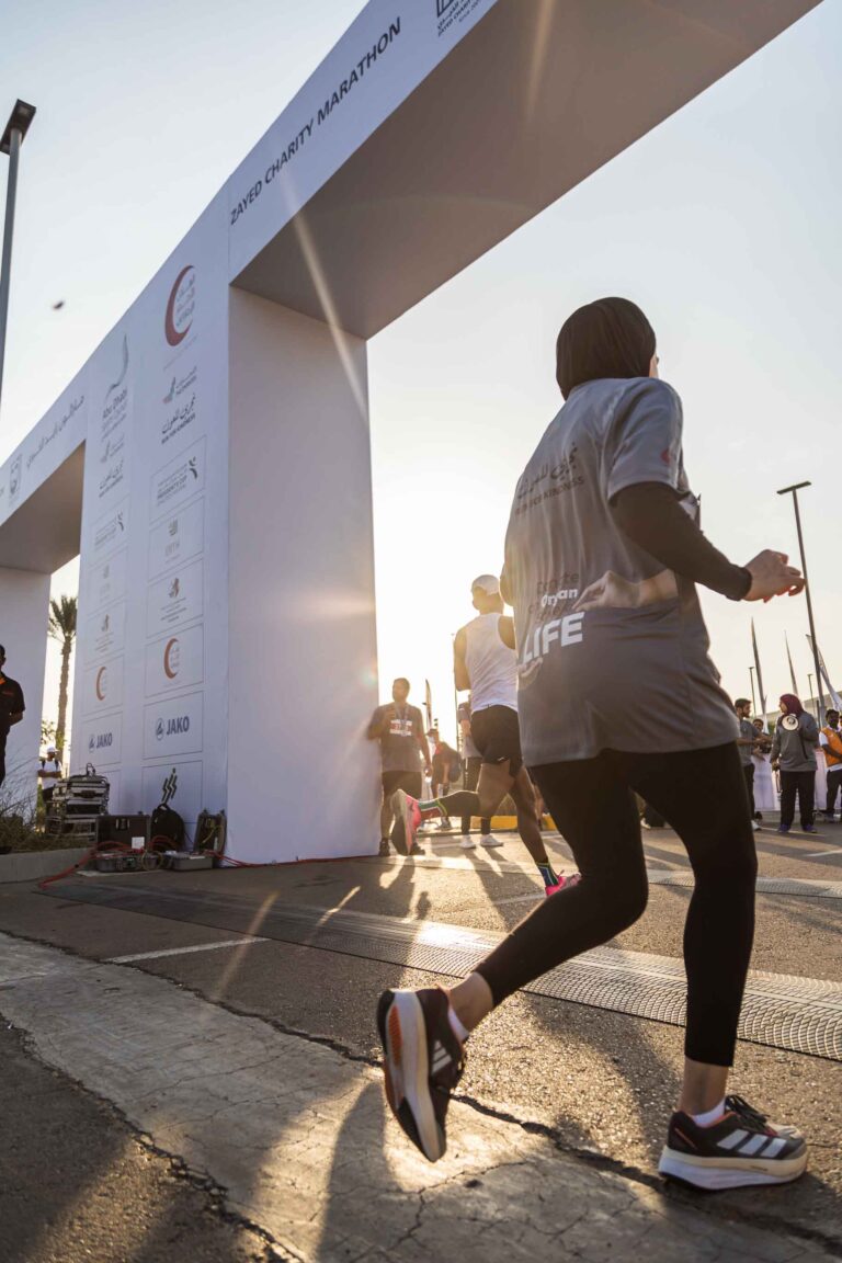 Hijabi runner crossing the finish line at the Zayed Charity Marathon Abu Dhabi 2022