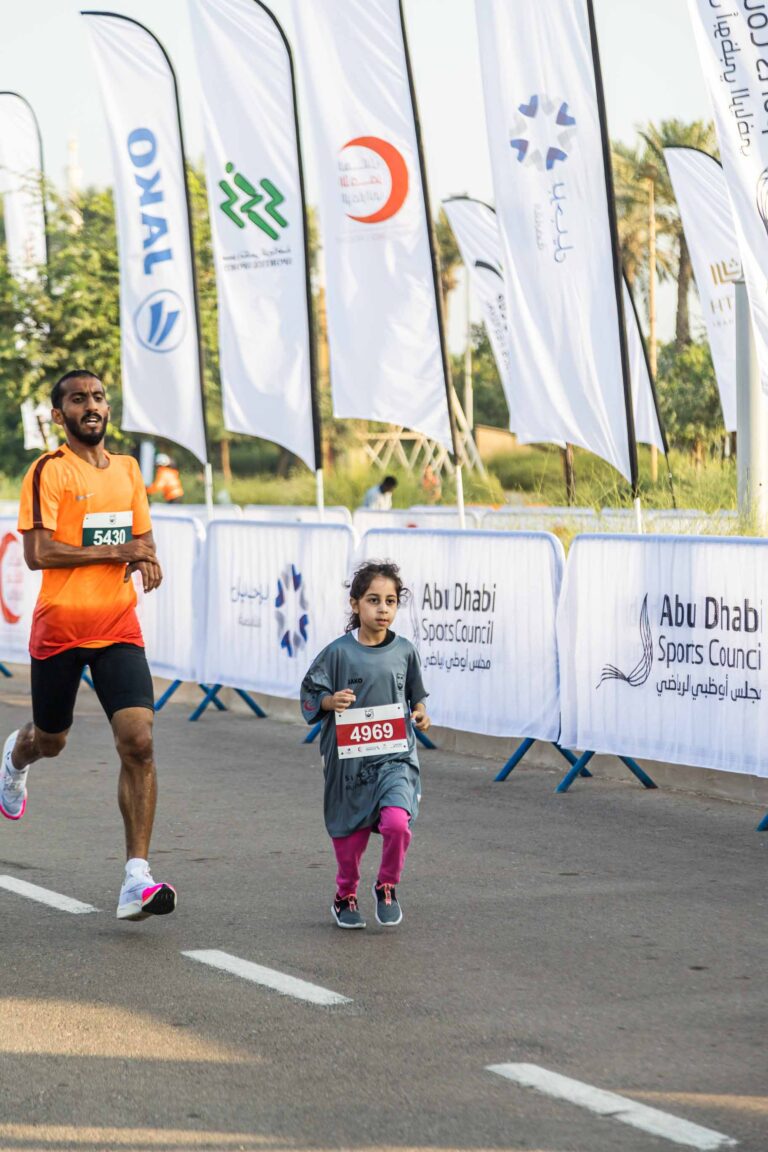 Child and athlete running in the Zayed Charity Marathon Abu Dhabi 2022
