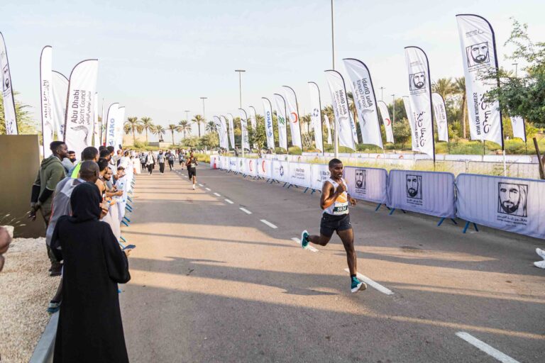 Spectators watching a runner running in the Zayed Charity Marathon Abu Dhabi 2022