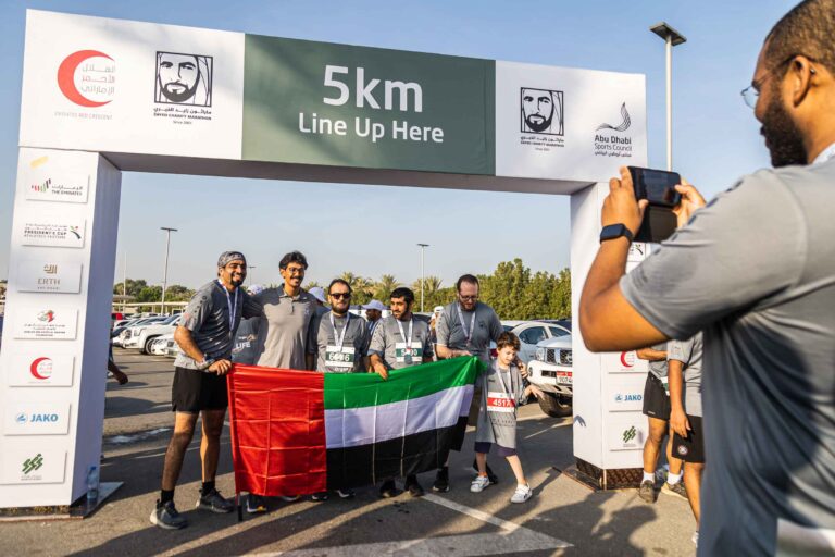 5k race runners posing for a photo with the UAE flag at the Zayed Charity Marathon Abu Dhabi 2022